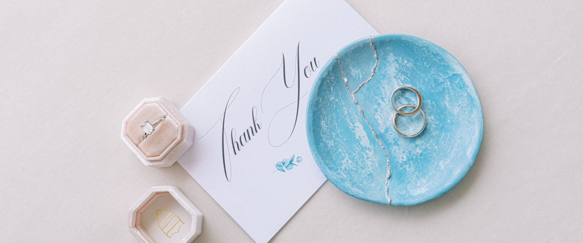 A wedding ring and a thank note placed on a blue plate, symbolizing the union of two hearts in a Mykonos wedding ceremony.