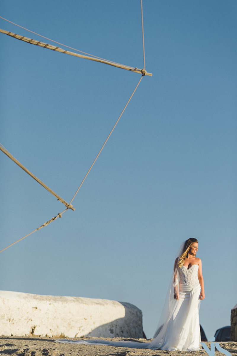 A beautiful bride standing in front of the iconic Mykonos windmills for the next day photoshoot, destination wedding in Mykonos
