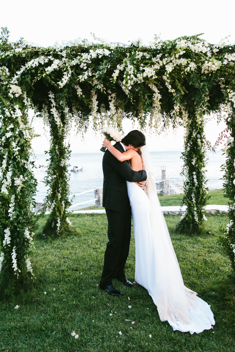 couple kissing under a flower gazebo in thie gorgeous destination wedding in Mykonos
