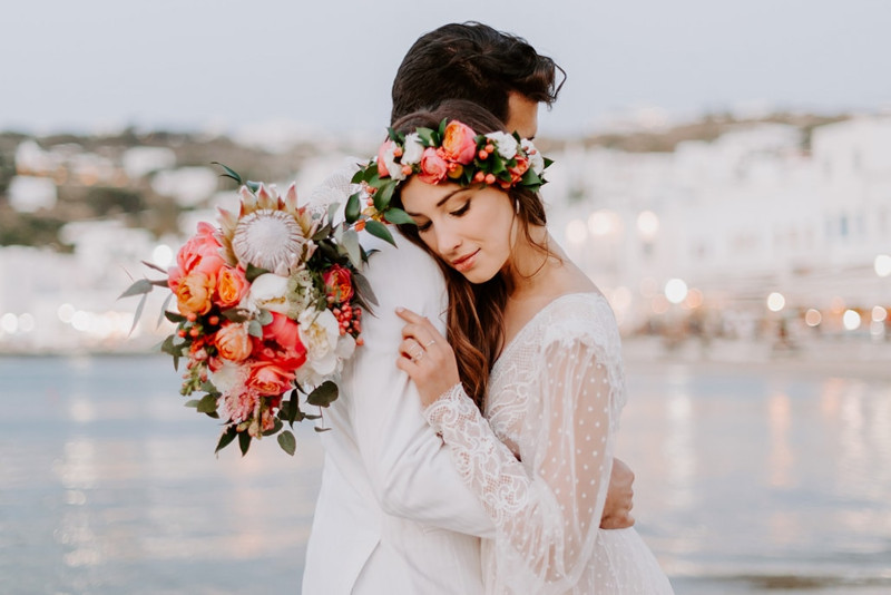 A professional photographer capturing a wedding ceremony in Mykonos, Greece, amidst stunning coastal scenery, wedding planning categories.